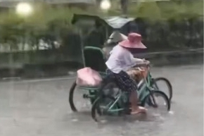 Xúc động em nhỏ còng lưng đạp xe, đẩy xe người khuyết tật khi mưa to, đường ngập