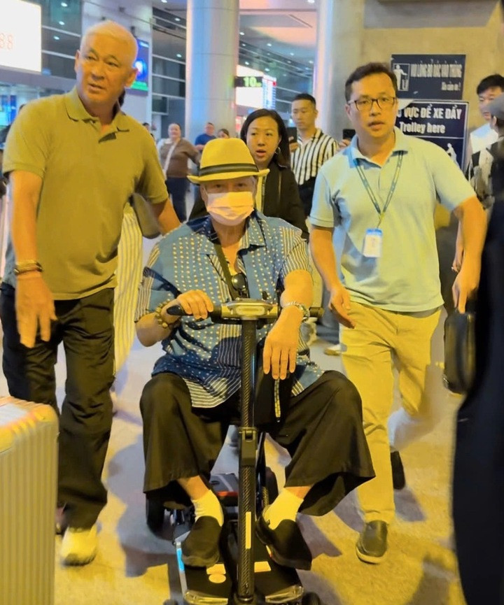 Nghệ sĩ Hồng Kim Bảo ngồi xe lăn, được vệ sĩ hộ tống.