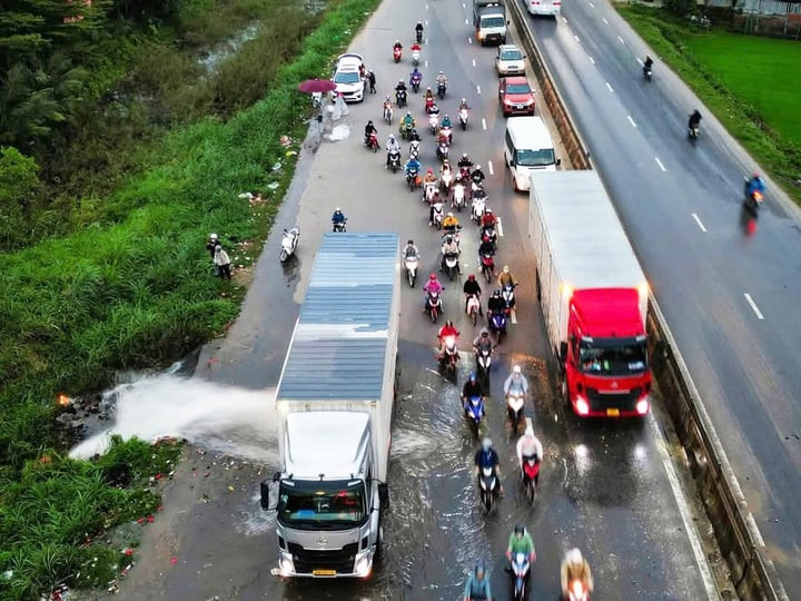 Xe container dừng lại 15 phút để chắn dòng nước, giúp hàng trăm xe máy đi qua. (Ảnh: T.C)