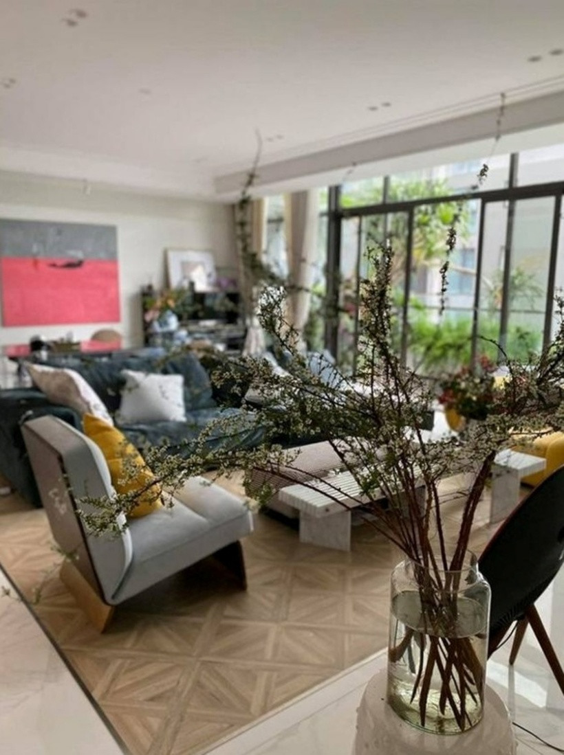 Phòng khách rộng rãi và ấm cúng với nội thất hiện đại. Gia đình Tùng Dương sử dụng bộ sofa mang màu sắc trung tính, tô điểm thêm cho căn phòng bằng những bình hoa tươi thắm.