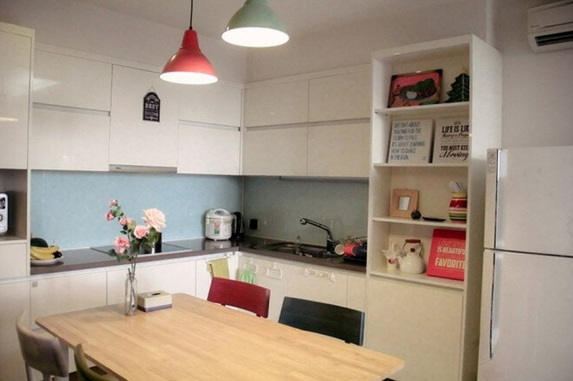 Phòng bếp nhỏ gọn, sử dụng gam màu trắng – patel và kết hợp nhiều món đồ trang trí tinh tế như hoa tươi, bảng gỗ in chữ tạo điểm nhấn dễ thương.