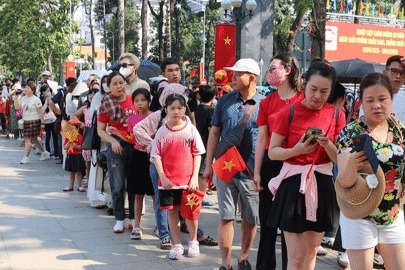 Người dân cầm cờ Tổ quốc, xếp hàng dài chờ tham quan Dinh Độc Lập trước lễ 30/4