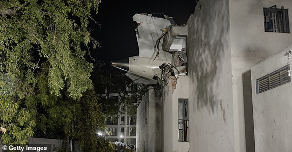 AHMEDABAD, ẤN ĐỘ - NGÀY 12 THÁNG 6: Đuôi máy bay nhô ra khỏi ký túc xá của trường đại học y sau khi một chiếc máy bay bị rơi ngay sau khi cất cánh vào ngày 12 tháng 6 năm 2025 tại Ahmedabad, Ấn Độ. Một chiếc Boeing 787 Dreamliner của Air India, chuyến bay AI-171, chở 242 hành khách và thành viên phi hành đoàn đang trên đường từ Ahmedabad đến London Gatwick, đã bị rơi ngay sau khi cất cánh vào ngày 12 tháng 6 năm 2025, sau khi phi công phát tín hiệu cấp cứu tới kiểm soát không lưu. Máy bay đã đâm vào khu vực Meghani Nagar đông dân cư gần Sân bay quốc tế Sardar Vallabhbhai Patel, gây ra một vụ nổ lớn và hỏa hoạn do tải trọng nhiên liệu quá lớn cho hành trình quốc tế, với các hoạt động cứu hộ đang diễn ra. (Ảnh của Elke Scholiers/Getty Images)