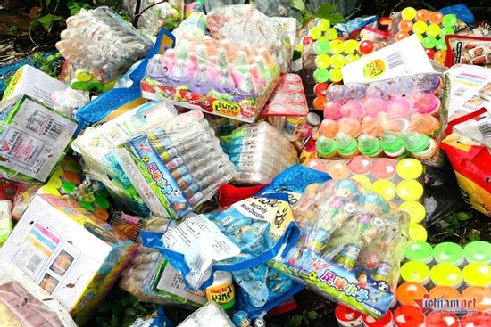 Hàng trăm gói kẹo đồ chơi trẻ em yêu thích đổ lộ thiên cạnh bãi rác