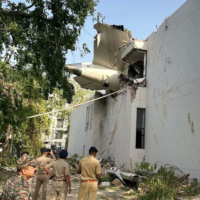 Air India crash site with police officers investigating debris and damage to a building after the accident.