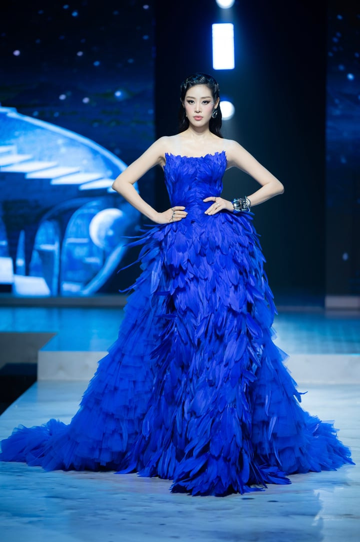 Thần Thái Rực Rỡ Của Khánh Vân Sau Kết Hôn Với Nhiếp Ảnh Gia Hơn 17 Tuổi Sau Hơn Nửa Năm Lên Xe Hoa, Hoa Hậu Khánh Vân Vừa Có Màn Tái Xuất Rực Rỡ Tại Sàn Diễn Thời Trang, Khẳng Định Đẳng Cấp Và Sức Hút Không Hề Thuyên Giảm Sau Khi Kết Hôn. Người Đẹp 9X Đảm Nhận Vai Trò Vedette. Trong Đêm Diễn, Khánh Vân Khoác Lên Mình Chiếc Váy Ôm Sát Đính Kết Hàng Trăm Chiếc Lông Vũ Màu Xanh Đặc Trưng. Dù Diện Bộ Váy Cồng Kềnh, Hoa Hậu Hoàn Vũ Việt Nam 2019 Vẫn Thể Hiện Thần Thái Kiêu Sa, Bước Đi Uyển Chuyển Đầy Bản Lĩnh, Nhận Tràng Vỗ Tay Không Ngớt Từ Khán Giả.
