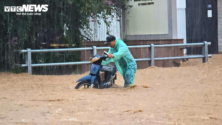 Một người dân vất vả dắt xe giữa dòng nước ngập.