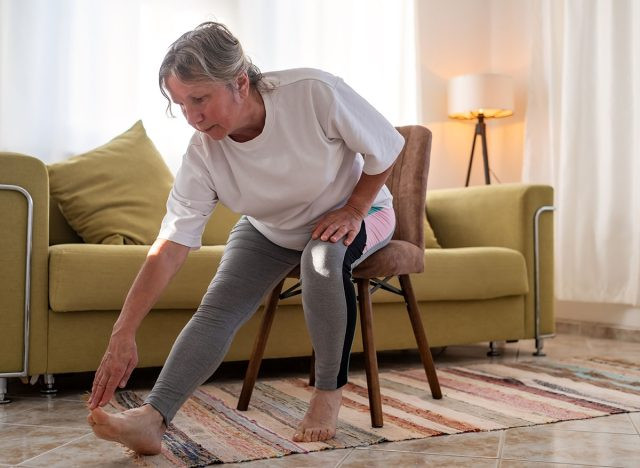 Người phụ nữ da trắng lớn tuổi đang tập yoga tại nhà trên ghế sofa