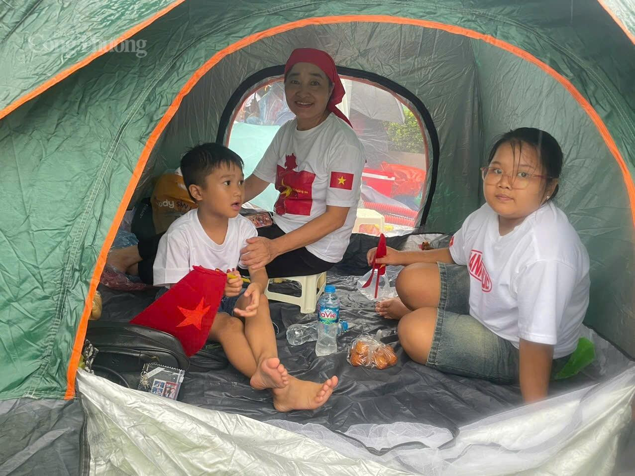 Cô Phạm Thị Bích Nhiễn (60 tuổi, áo trắng) ở Phú Thọ cho hay: ”Gia đình cô từ Phú Thọ tới Hà Nội lúc từ 3h sáng. Vì trời mưa to nên gia đình mang theo lều dựng tạm cho các cháu không bị ướt, hơn nữa thời gian chờ cũng khá lâu nên cô mang theo cả đồ ăn, nước uống, quần áo để thay nếu bị ướt”.