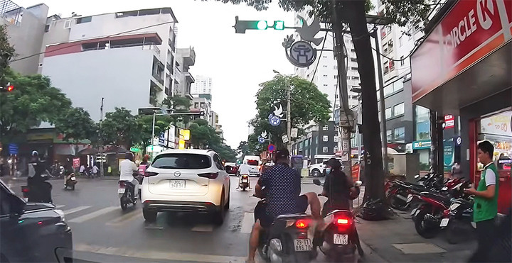 Sau khi húc xe máy của người phụ nữ dừng đèn đỏ, người đàn ông giơ chân dọa đạp. (Ảnh cắt từ clip)