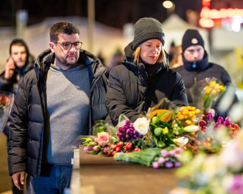 Những người đến viếng đứng gần quầy bar Le Constellation bên cạnh những bó hoa.