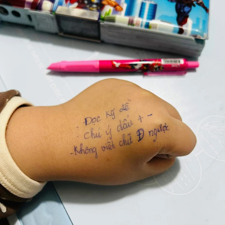 Đôi bàn tay nhỏ, được mẹ ghi chú những dòng dặn dò trước ngày thi.