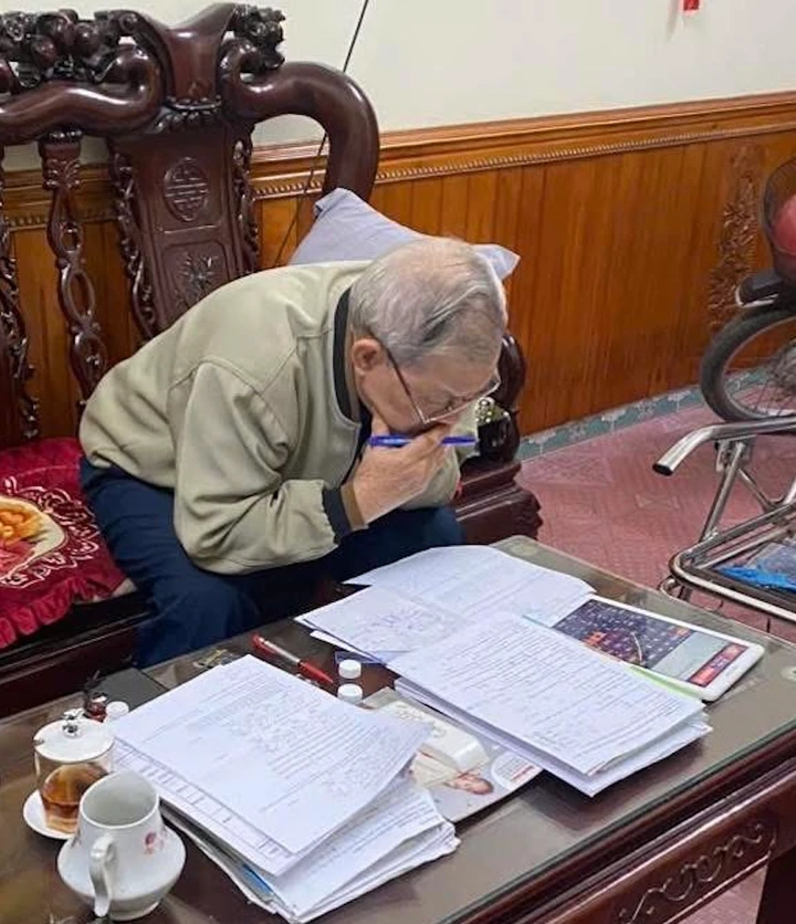 Hình ảnh người ông học bài để ôn thi cùng cháu.