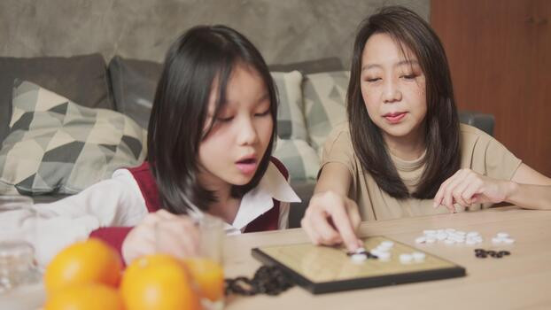 asian mom and kid fun playing go checkers board game on table in home living room together with love and cheerful happy weekend relaxing hobby of child and family concentrate and compete video