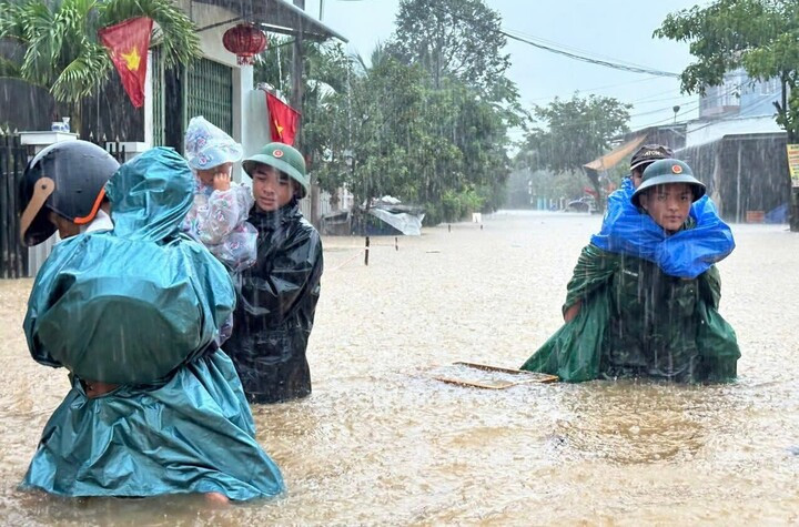 Lực lượng chức năng hỗ trợ người dân ở xã Núi Thành sơ tán khỏi khu vực ngập sâu. (Ảnh: Q.C)