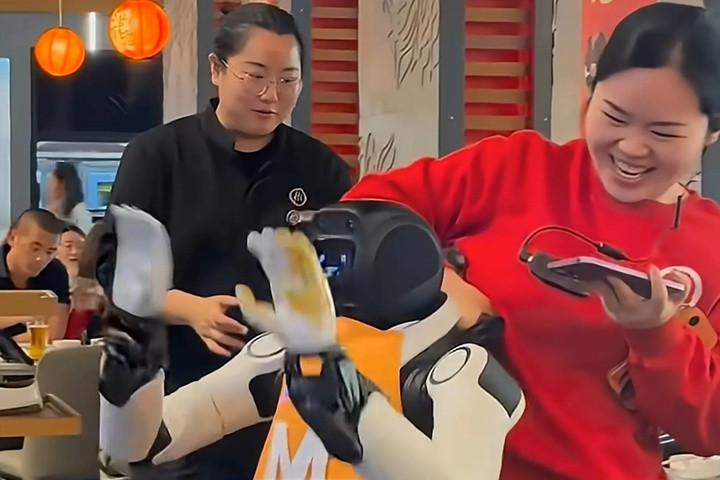 Các nhân viên nhà hàng giữ chặt robot và kéo ra khỏi khu vực phục vụ.
