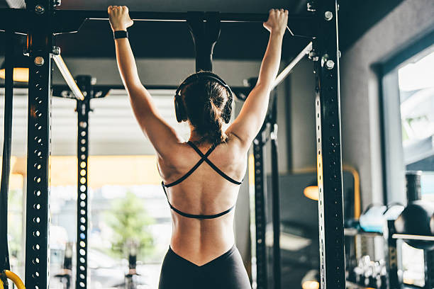 unrecognizable fit woman doing resistance band assisted pull ups in gym 17749512914691185764890