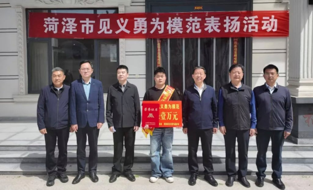 Officials, above, presented Zhang, centre, with a banner and a cash prize for the bravery he showed. Photo: QQ.com