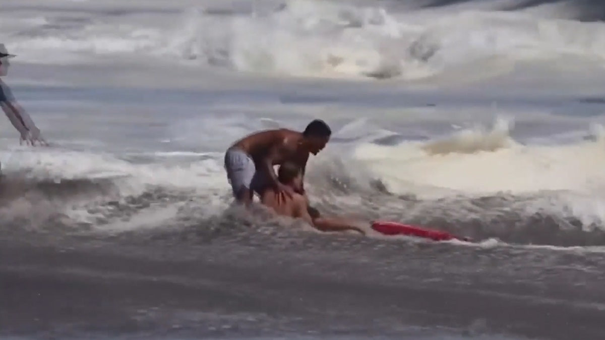 Quyết không buông tay bé trai giữa sóng dữ, nam cứu hộ 16 tuổi gây sốt toàn cầu插图 man pulls lifeguard holding kid