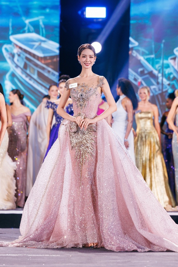 Hoa hậu Bảo Ngọc hút trọn ống kính truyền thông khi diện đầm dạ hội bồng bềnh tông màu hồng. Thiết kế thuộc bộ sưu tập Xuân Hè mới nhất của JoliPoli, từng được giới thiệu tại Thượng Hải. Bộ váy mất hơn 120 giờ để đính kết với hơn 5.000 viên pha lê và đá Swarovski.